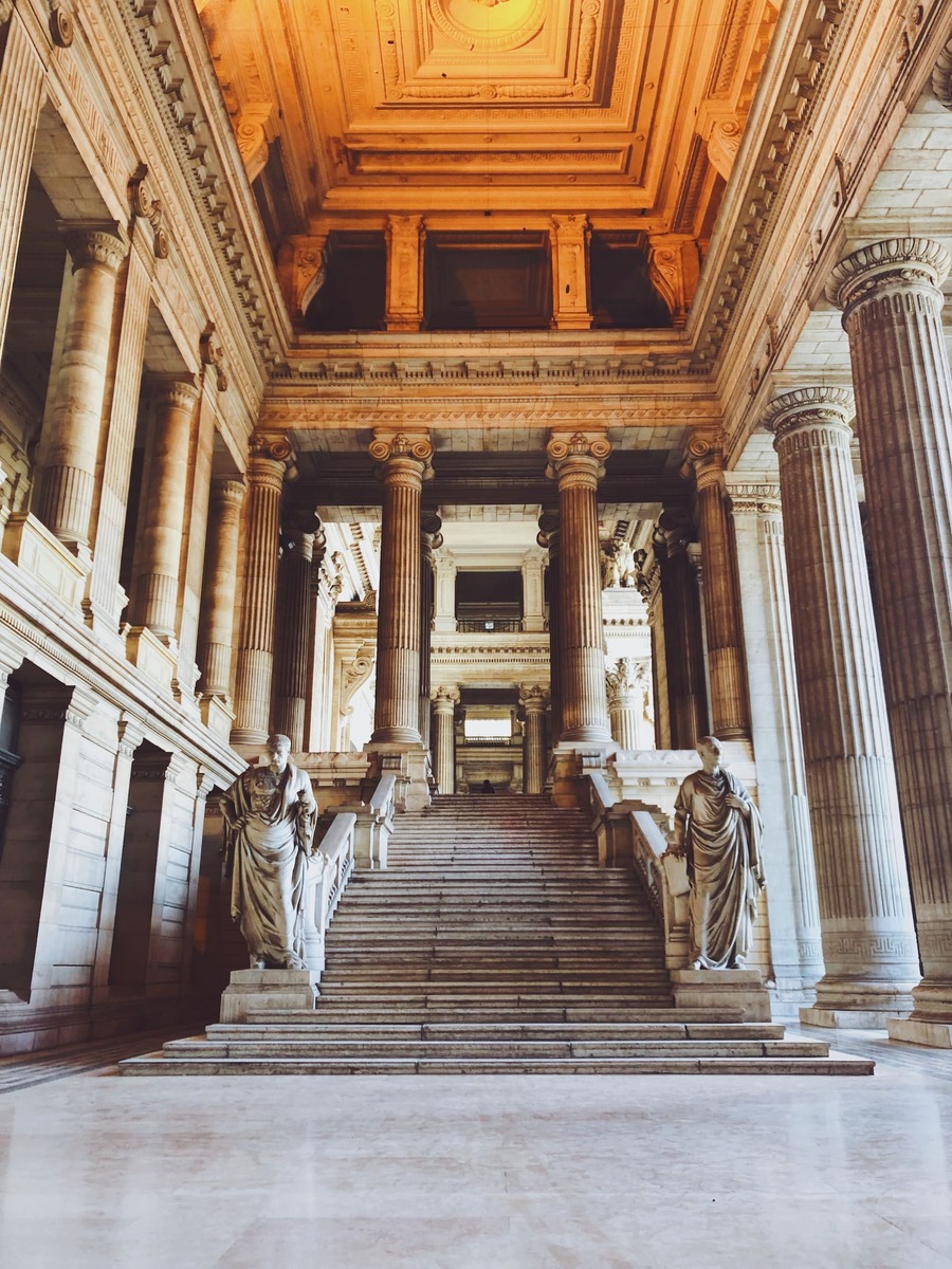 Intérieur majestueux d'un palais de justice avec des colonnes corinthiennes et un plafond richement détaillé.